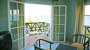 Een kamer met balkon, een tafel, twee stoelen en een televisie.