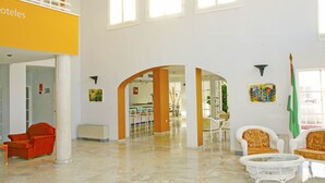 Een ruime hotellobby met een hoge plafond, een receptie en een eetgedeelte.