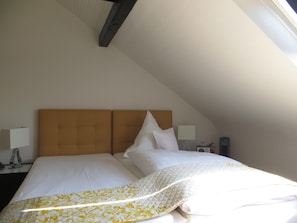 Una cama individual con cabecera de madera en una habitación con techos inclinados.