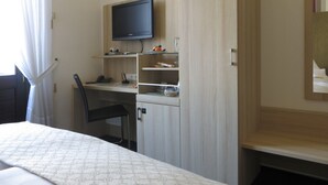 A hotel room with a bed, a desk with a computer, a chair, and a TV mounted on the wall. - Hotel Kronprinzen (Bonn)