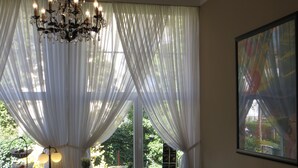 A dining area with a table set for four, a chandelier, and sheer white curtains. - Hotel Kronprinzen (Bonn)