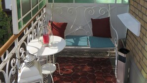 A sunlit room with a green-framed window, a white metal bed, and a small table with a red candle. - Hotel Kronprinzen (Bonn)