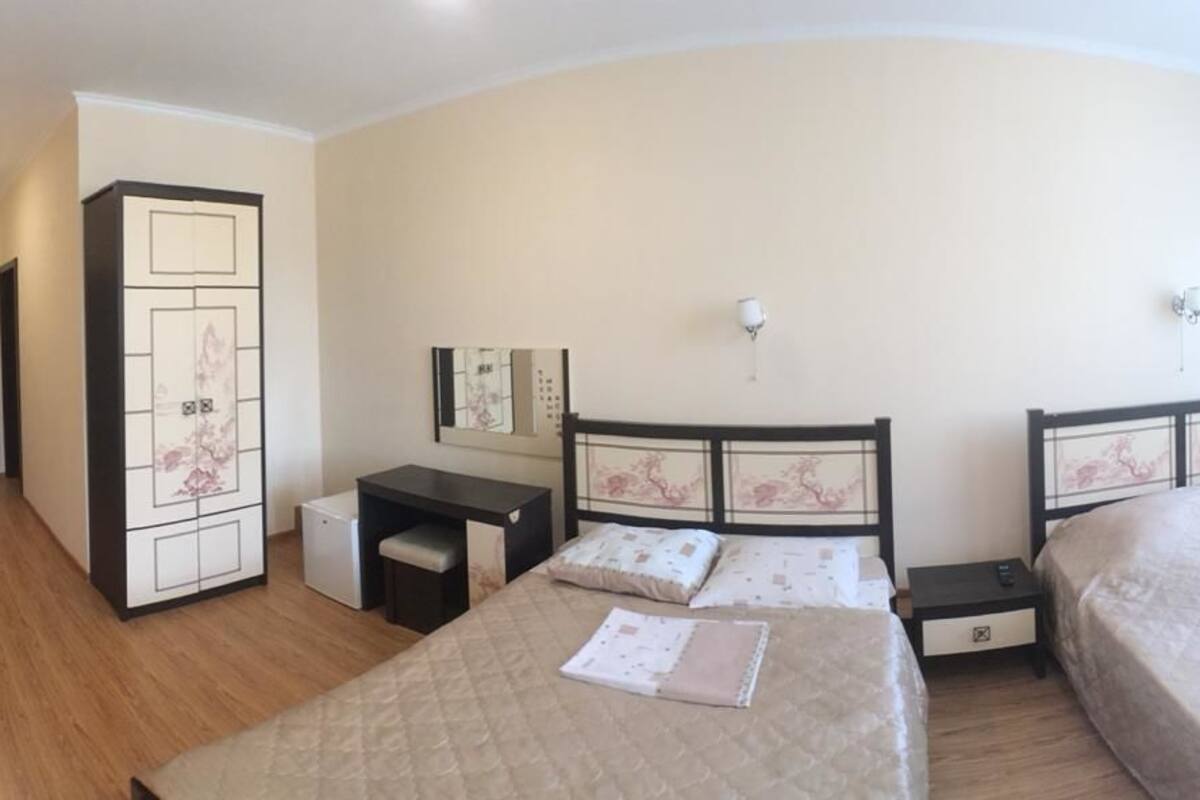 A bedroom with two beds, a desk, a wardrobe, and a mirror.