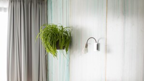 Una habitación de hotel con una cama, un escritorio y una planta colgante.