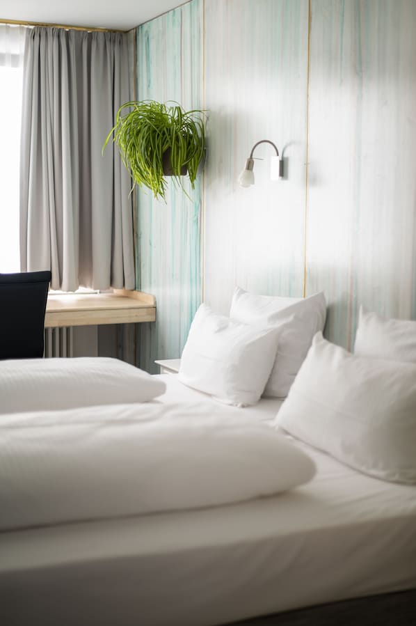 A hotel room with a bed, a desk, and a hanging plant. - Abalon Hotel Ideal (Stuttgart)