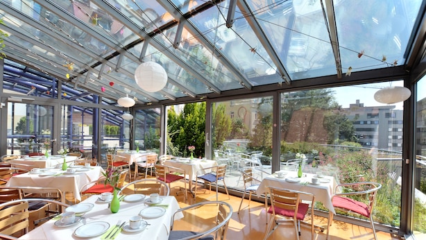 Un restaurante con paredes de vidrio, mesas dispuestas para comer y vistas de la ciudad.