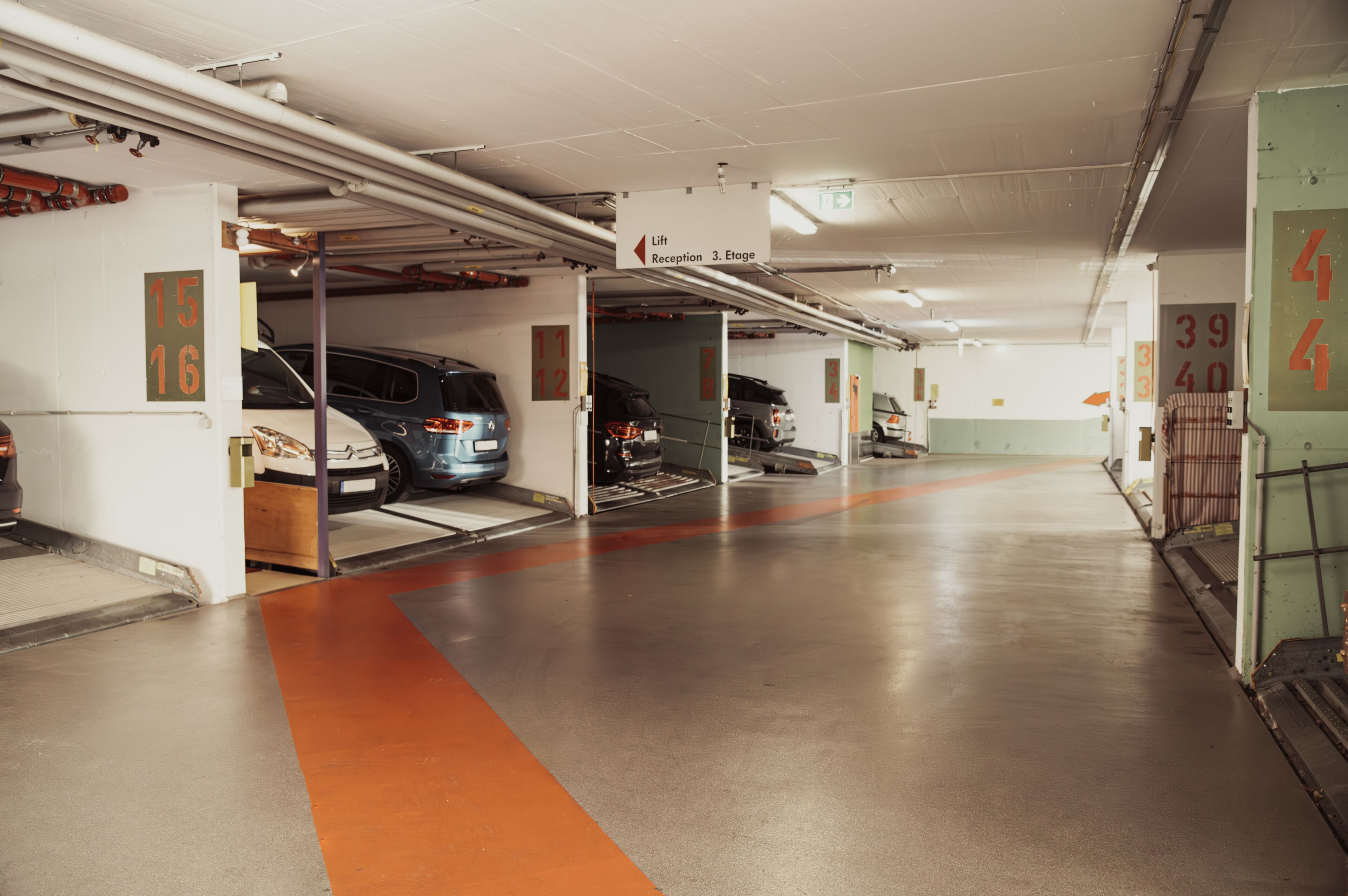Um parque de estacionamento com vários níveis, com espaços bem demarcados e sinalização indicativa.