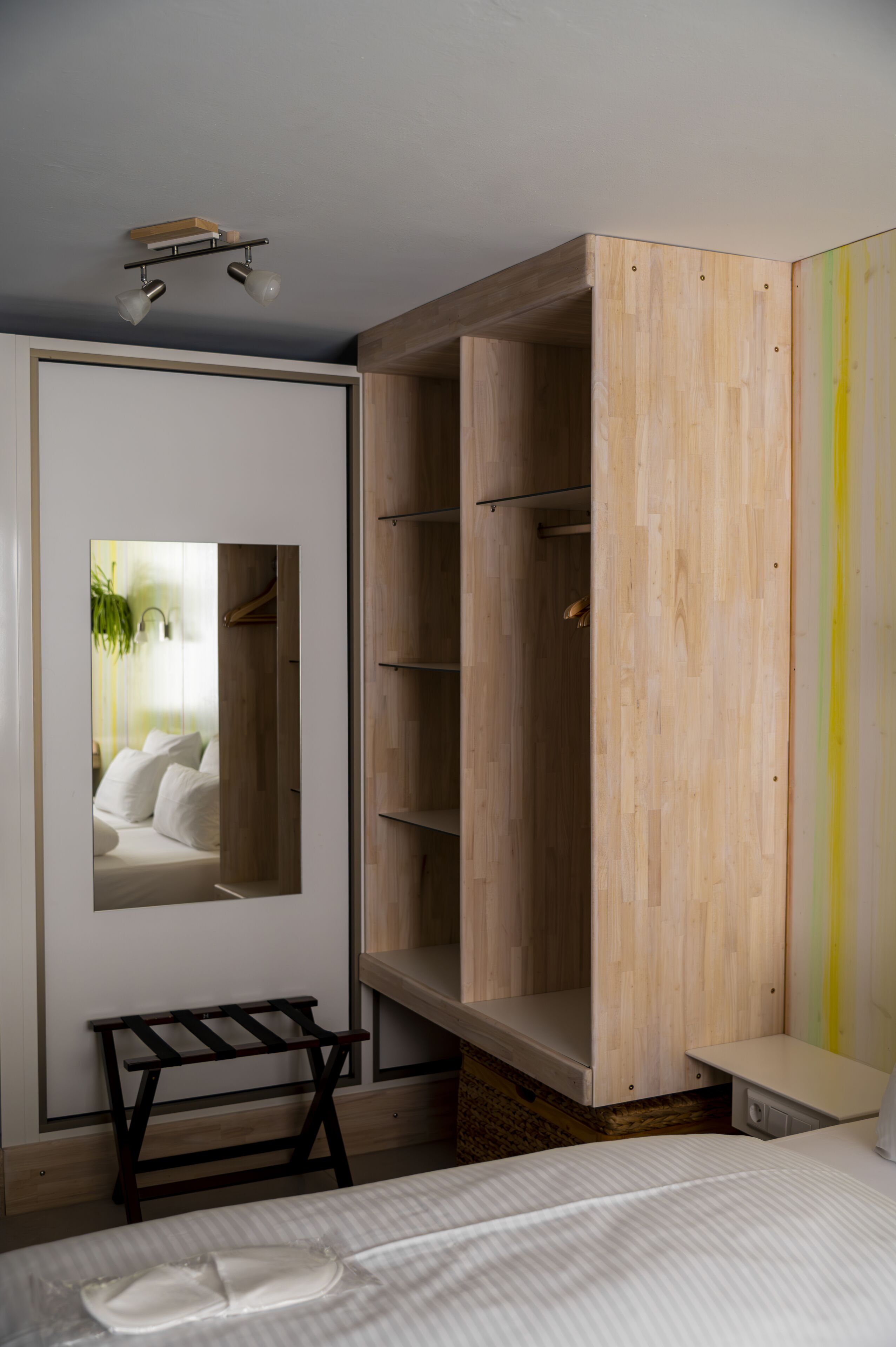 Un dormitorio con una cama, un armario de madera, un espejo y un pequeño banco.