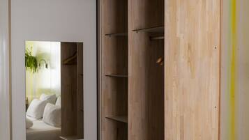 Un dormitorio con una cama, un armario de madera, un espejo y un pequeño banco.