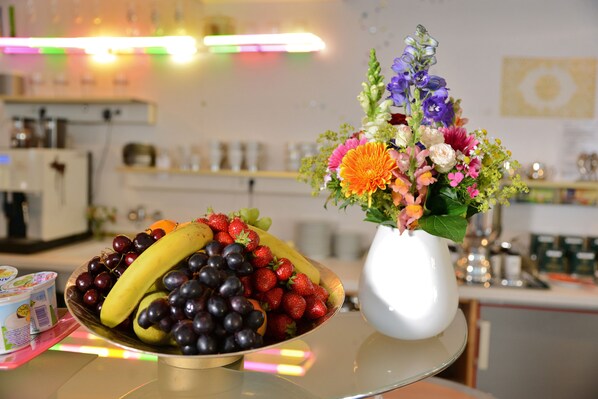 A table with a fruit bowl and a vase of flowers. - Abalon Hotel Ideal (Stuttgart)