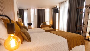Una habitación de hotel moderna con una cama grande, mesitas de noche, televisión y armario.
