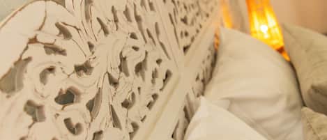 Un lit doté d’une tête de lit décorée et de linge de lit blanc.