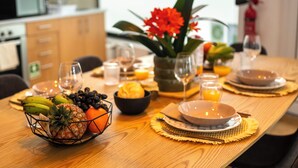Una mesa de comedor servida con platos, tazones y una cesta de frutas.