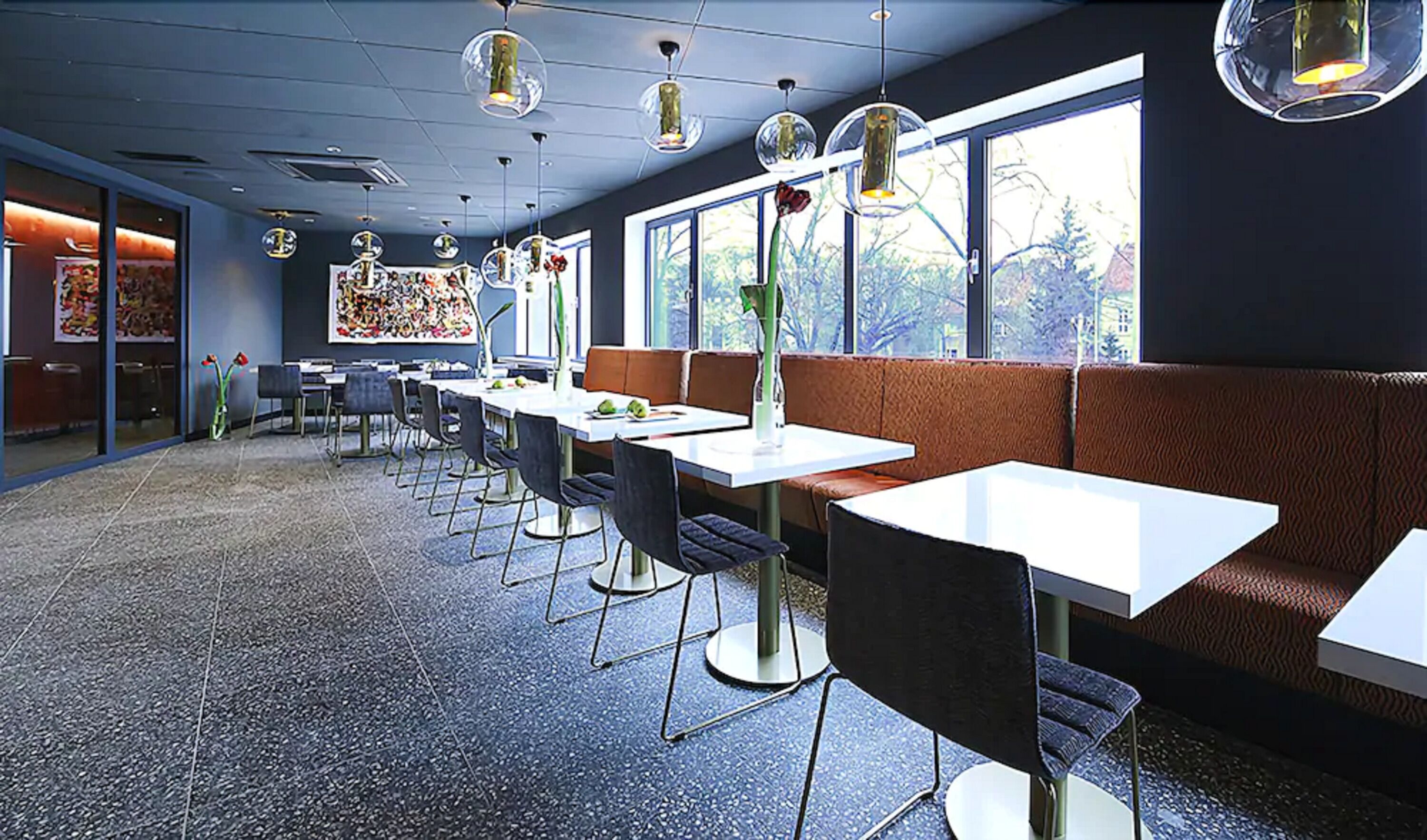 A modern dining area with long tables, black chairs, and a patterned carpet.
