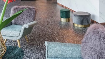 Un área de recepción moderna con mostrador de mármol, plantas colgantes y una lámpara de techo original.