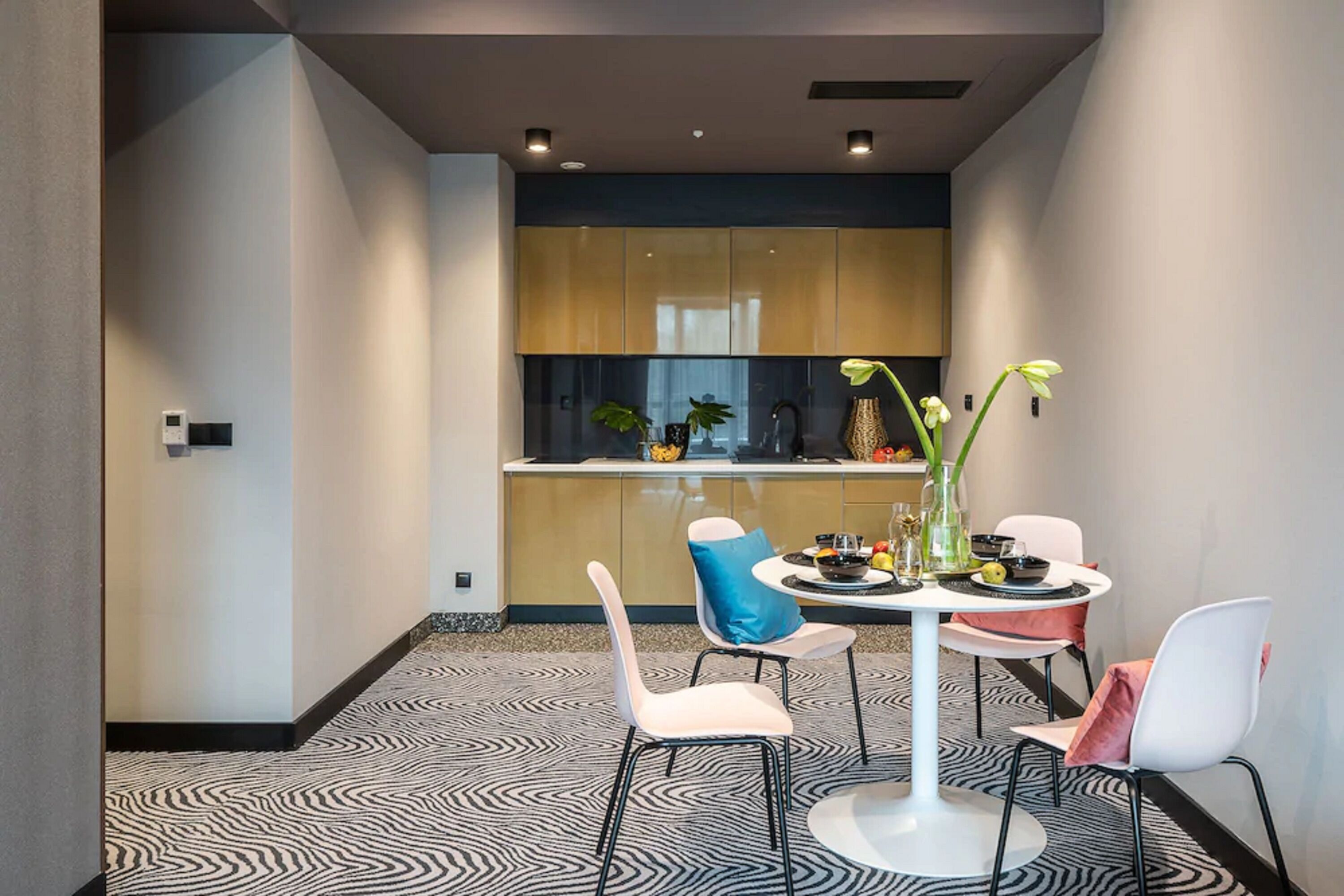 A modern dining area with a round table, white chairs, and a patterned floor.