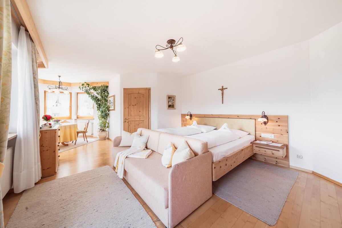 A bedroom with a large bed, wooden headboard, bedside tables, a nightstand, and a wooden wardrobe.