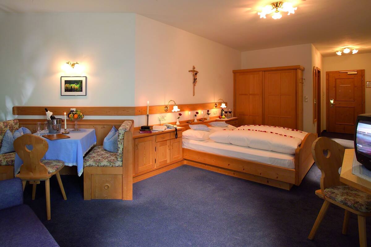 A cozy room with a bed, a sofa, a dining table, and a TV.