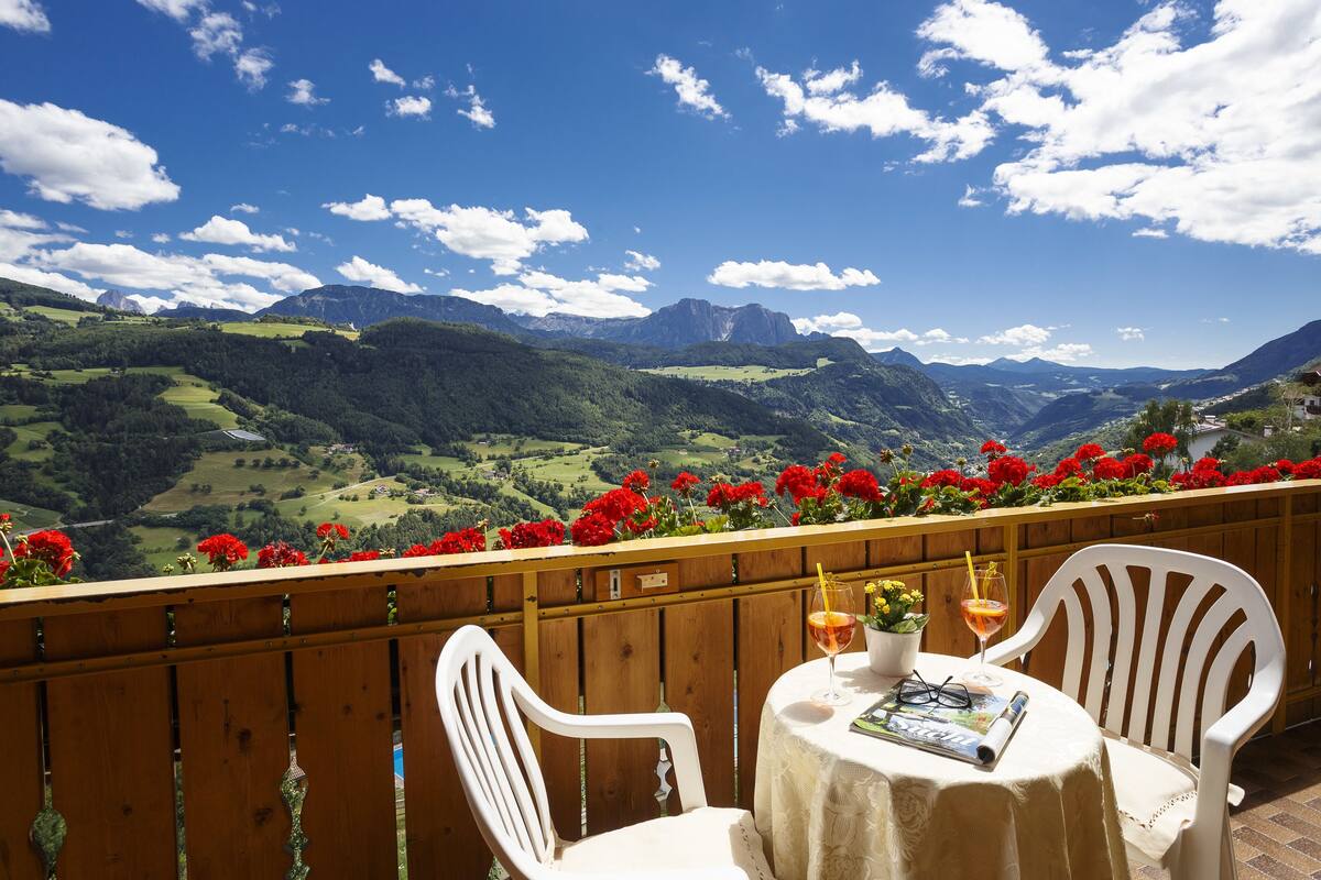 A balcony with a table, chairs, and a view of mountains.