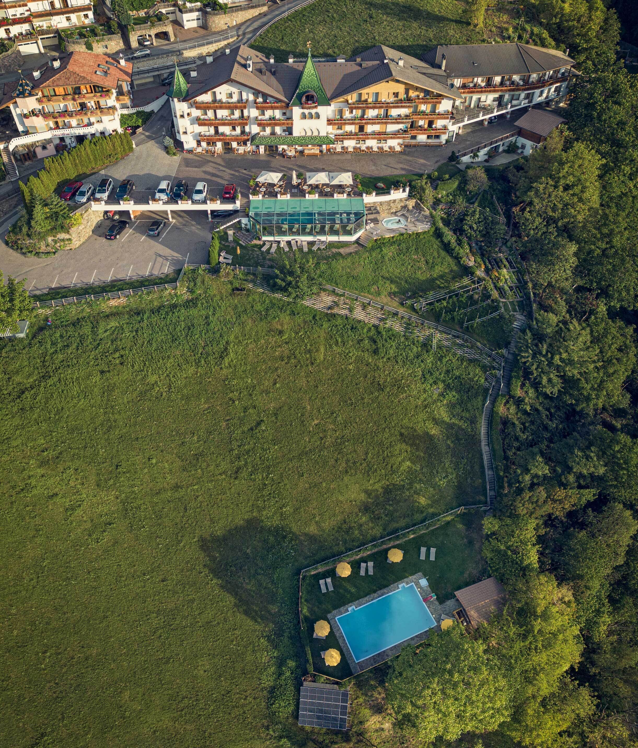 Vue aérienne d’un complexe hôtelier comprenant plusieurs bâtiments, une piscine et un parking.