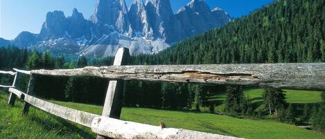 A rustic wooden fence in a mountainous landscape with a clear view of rugged peaks in the background.