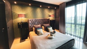 Een moderne slaapkamer met een groot bed, twee nachtkastjes en uitzicht op groen door het raam.