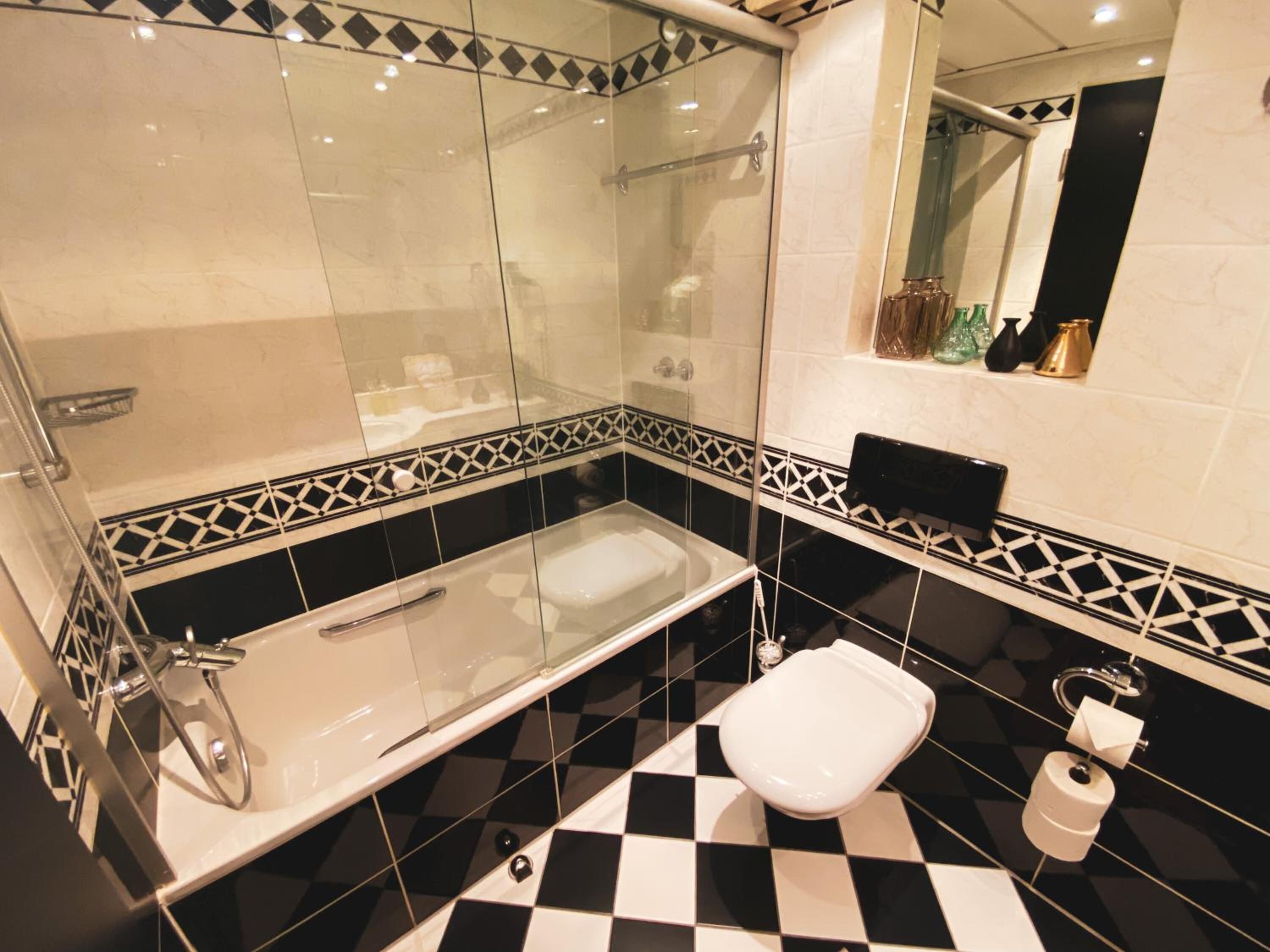 Un baño moderno con ducha de vidrio, bañera independiente y retrete.