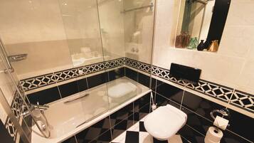 Un baño moderno con ducha de vidrio, bañera independiente y retrete.
