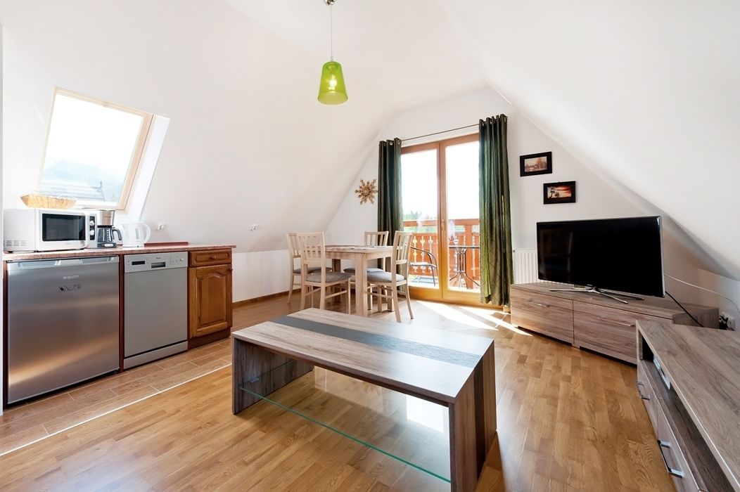 Une cuisine moderne avec un coin repas, un téléviseur et un balcon agrémenté de rideaux.