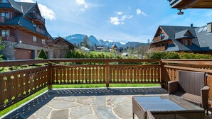 A patio area with stone flooring, wicker furniture, and a wooden fence with heart-shaped cutouts. - Apartamenty Sun&Snow Lipki Park Zakopane (Zakopane)