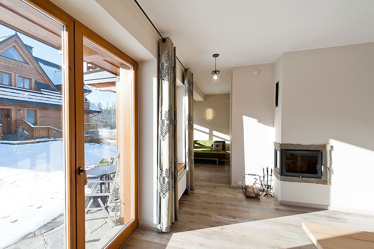 Una habitación amplia con un gran ventanal, una chimenea y vista a un edificio.