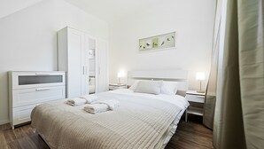 A neatly arranged hotel room with a bed, bedside tables, a wardrobe, and a wall-mounted artwork. - Apartamenty Sun&Snow Lipki Park Zakopane (Zakopane)