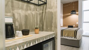 Een kitchenette met een koffiezetapparaat, bekers, een kom en een cactus.