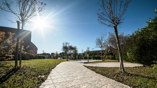 A paved pathway in a park-like setting with trees and a clear sky. - Family Hotel (Polla)