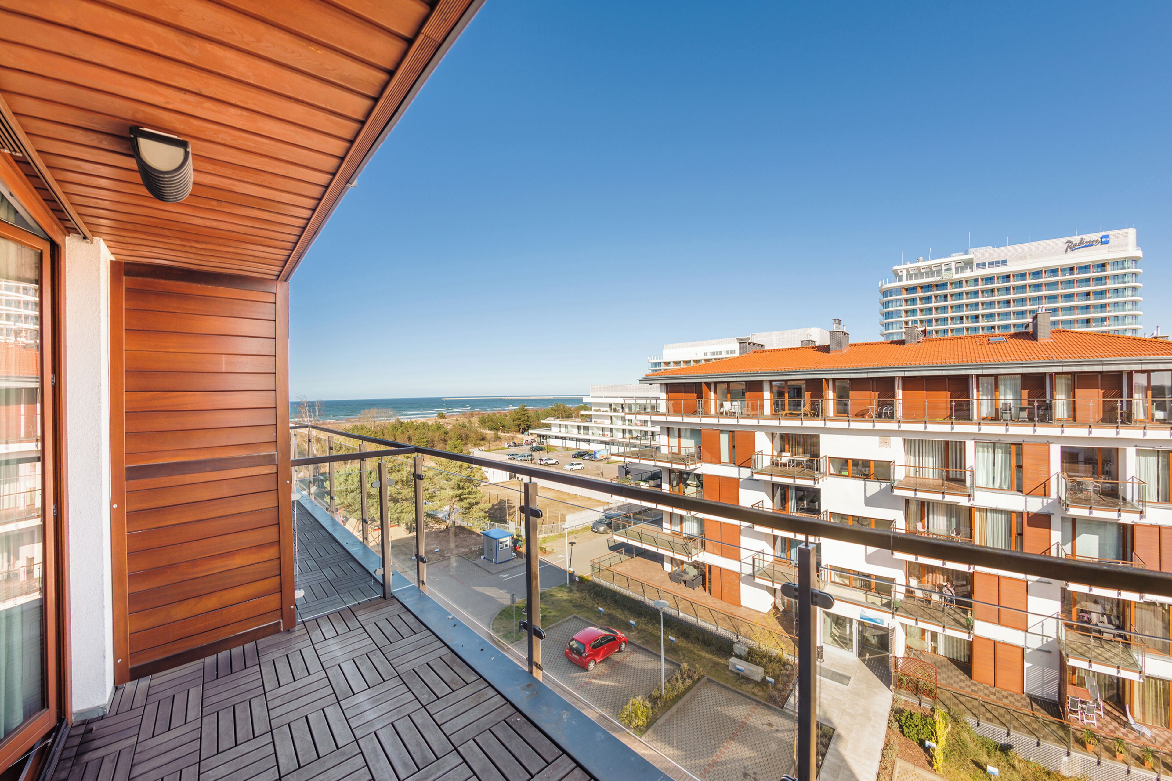 Ein modernes Hotel mit Holzbalkon, mehreren Etagen und Meerblick.