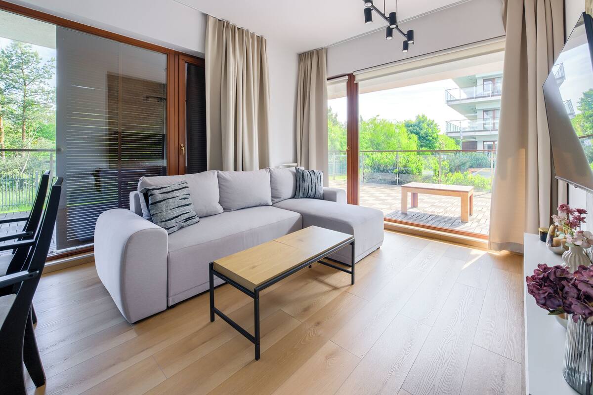 A modern living room with a sofa, a coffee table, and a TV mounted on the wall.