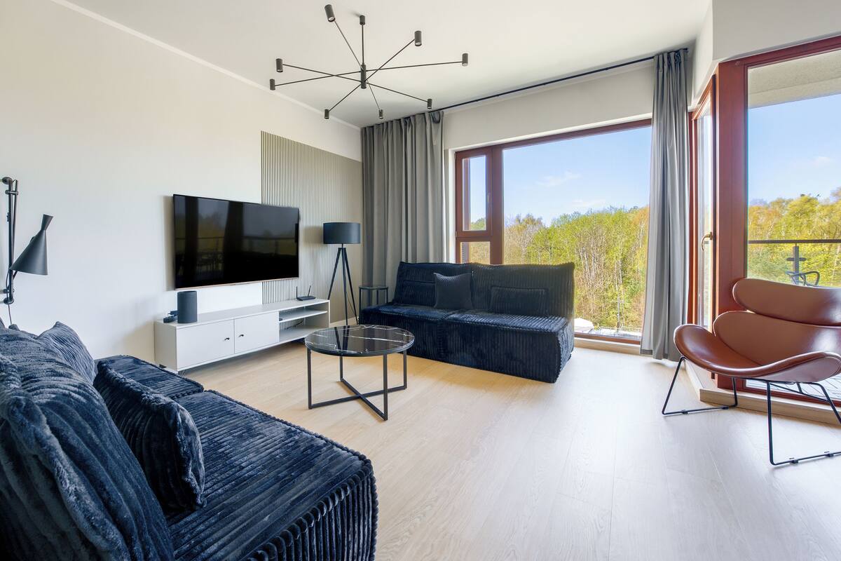 A modern living room with a flat-screen TV, a sofa, a coffee table, and a chair.