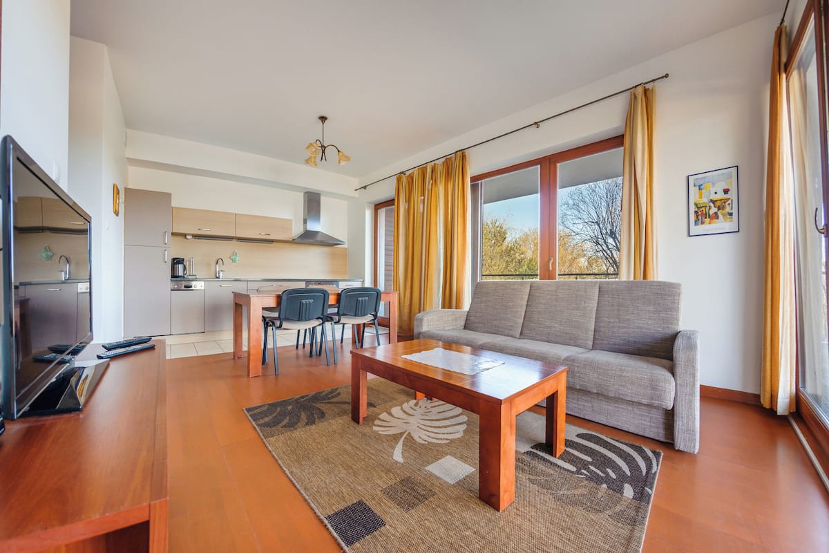 A modern living room with a sofa, coffee table, and dining area.