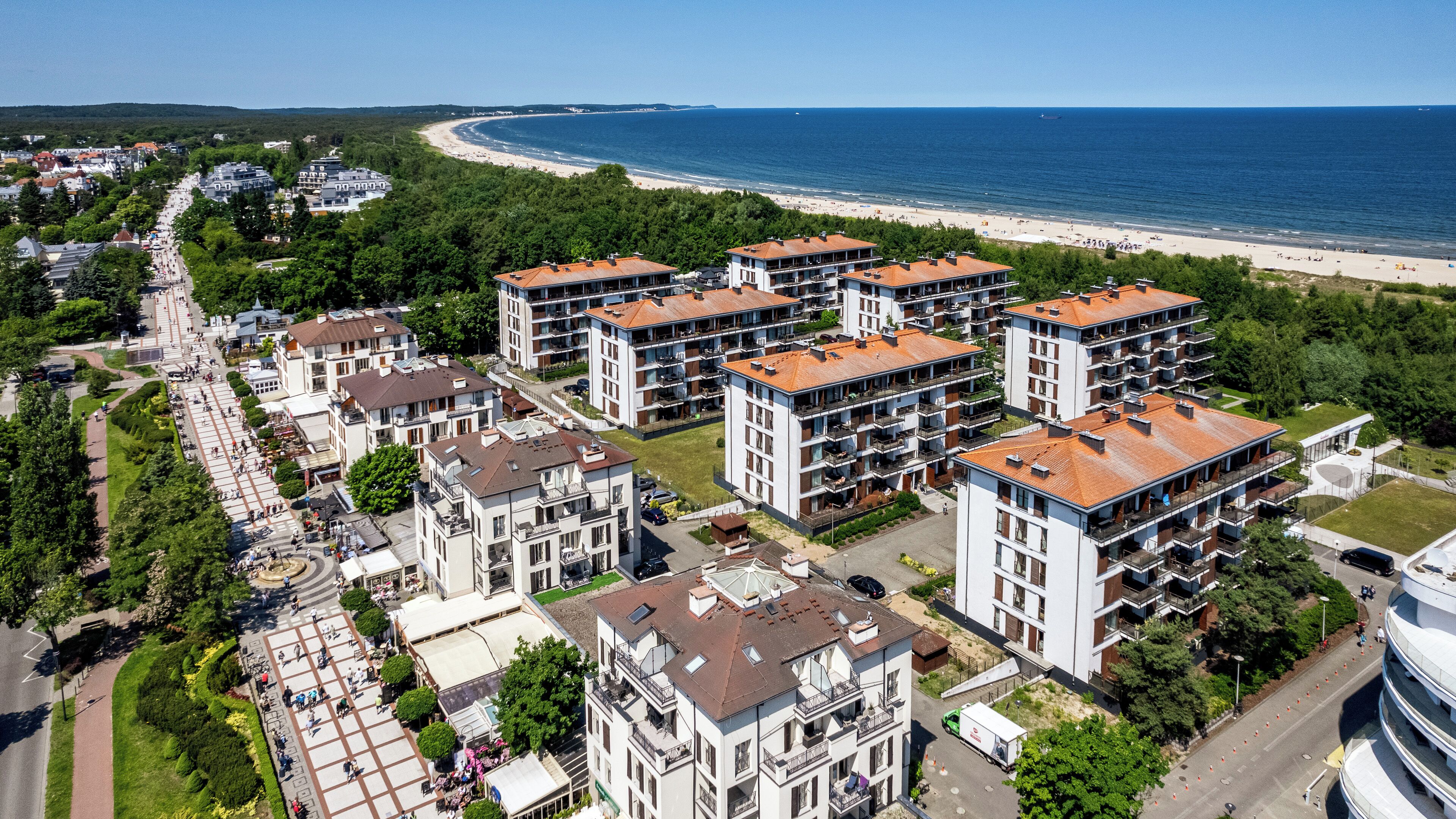 A high-rise residential building complex with multiple balconies, a central courtyard, and a view of the beach and sea.