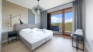 A modern hotel room with a large bed, a bedside table, a lamp, and a view of the outdoors. - Apartamenty Sun & Snow Plaża (Swinoujscie)