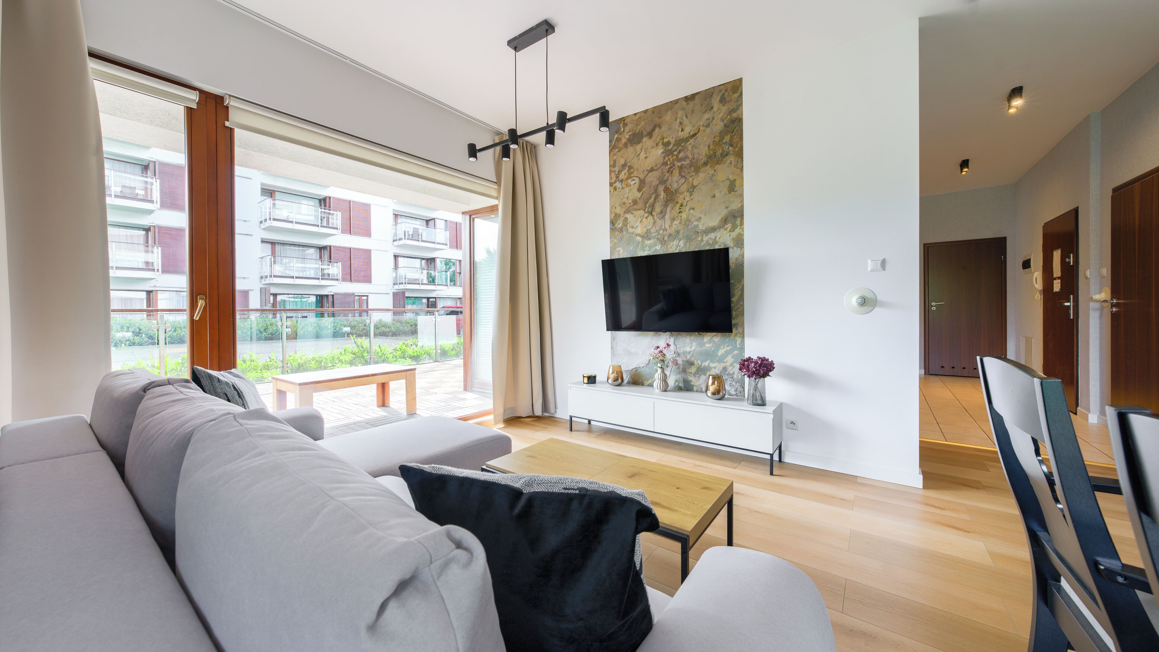 A modern living room with a sofa, a coffee table, and a TV mounted on the wall.