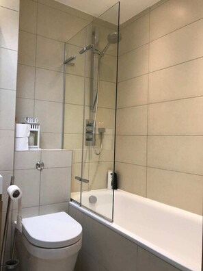 A modern bathroom with a glass-enclosed shower, a white toilet, and a bathtub.