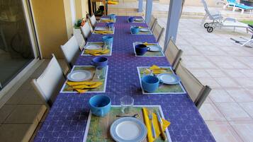 A dining table set with blue and yellow tableware, chairs, and a view of the outdoor area.