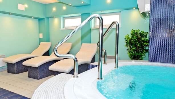 A spa area with a pool, lounge chairs, and a staircase leading to the pool.