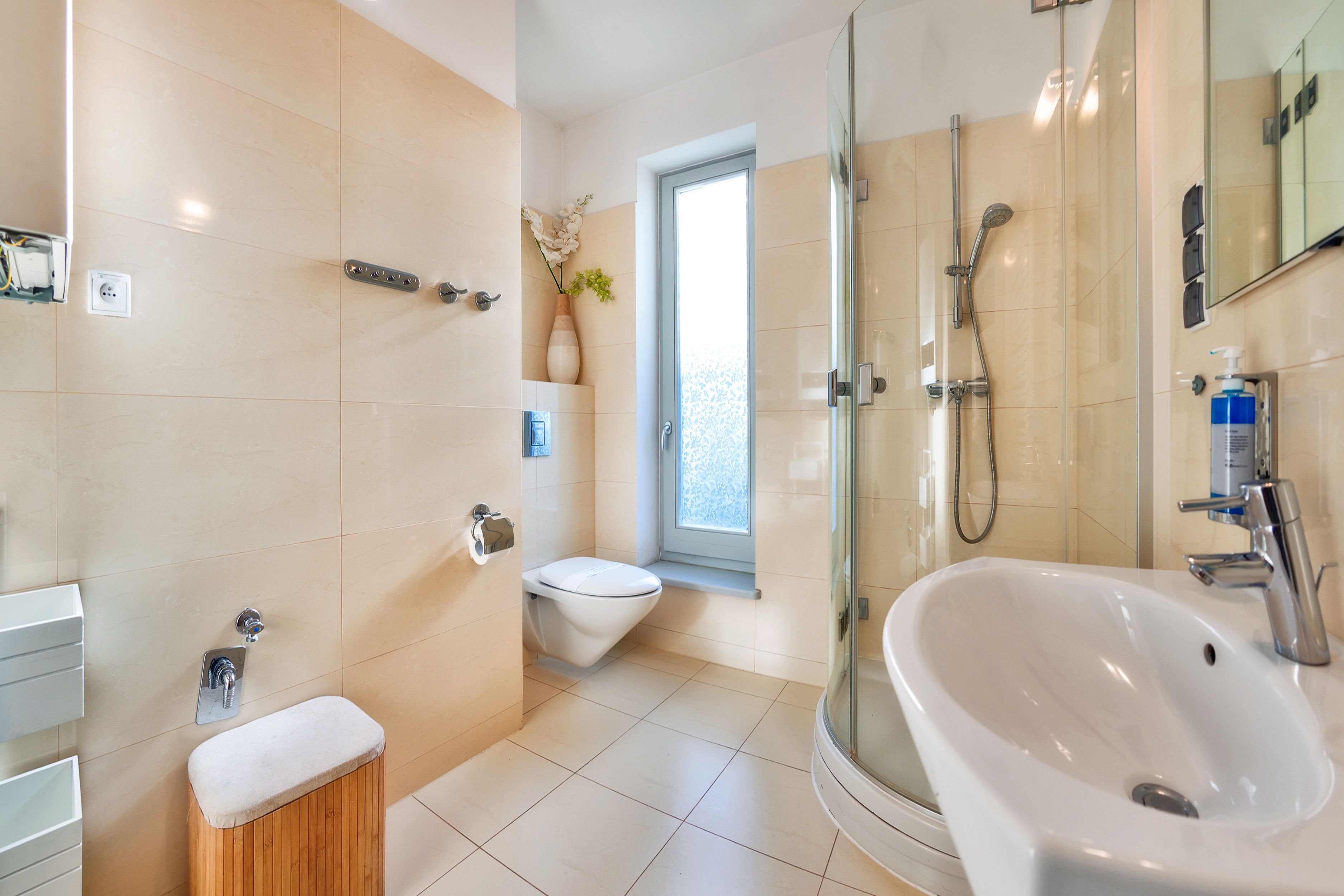 A modern bathroom with a glass shower enclosure, a white sink, and a toilet.