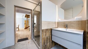 A modern bathroom with a white vanity, a large mirror, and a tiled backsplash.