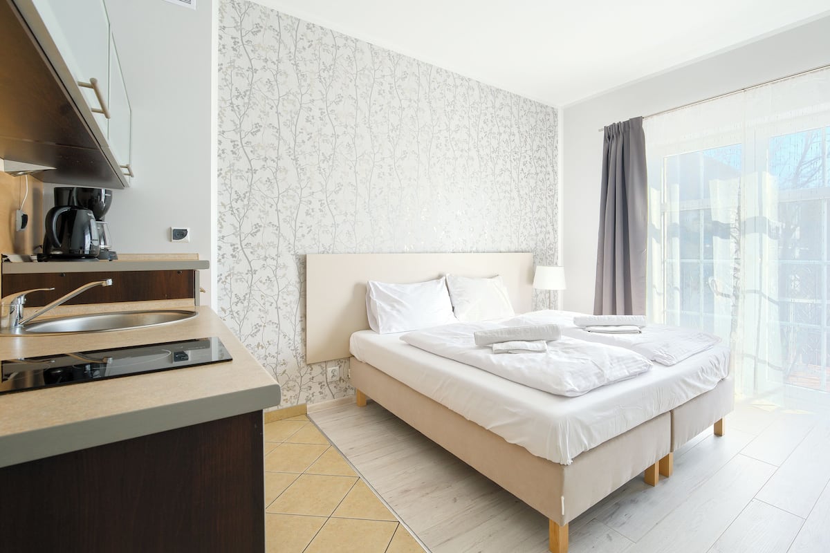 Une chambre d’hôtel avec un lit, une table de chevet avec une lampe, une fenêtre avec des rideaux et une vue sur l’extérieur.
