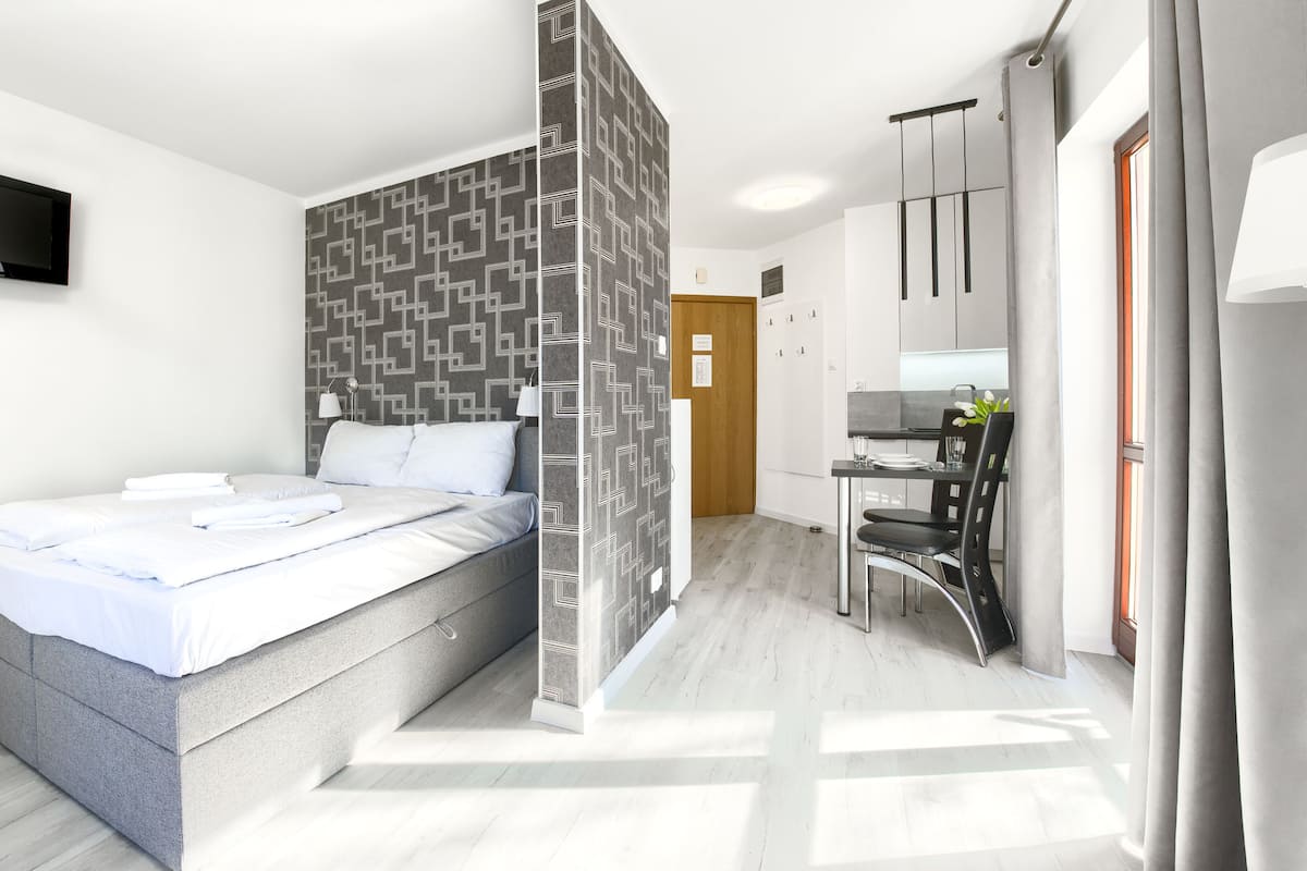 Une chambre d’hôtel moderne équipée d’un lit, d’une télévision, d’un coin repas et d’une salle de bain.