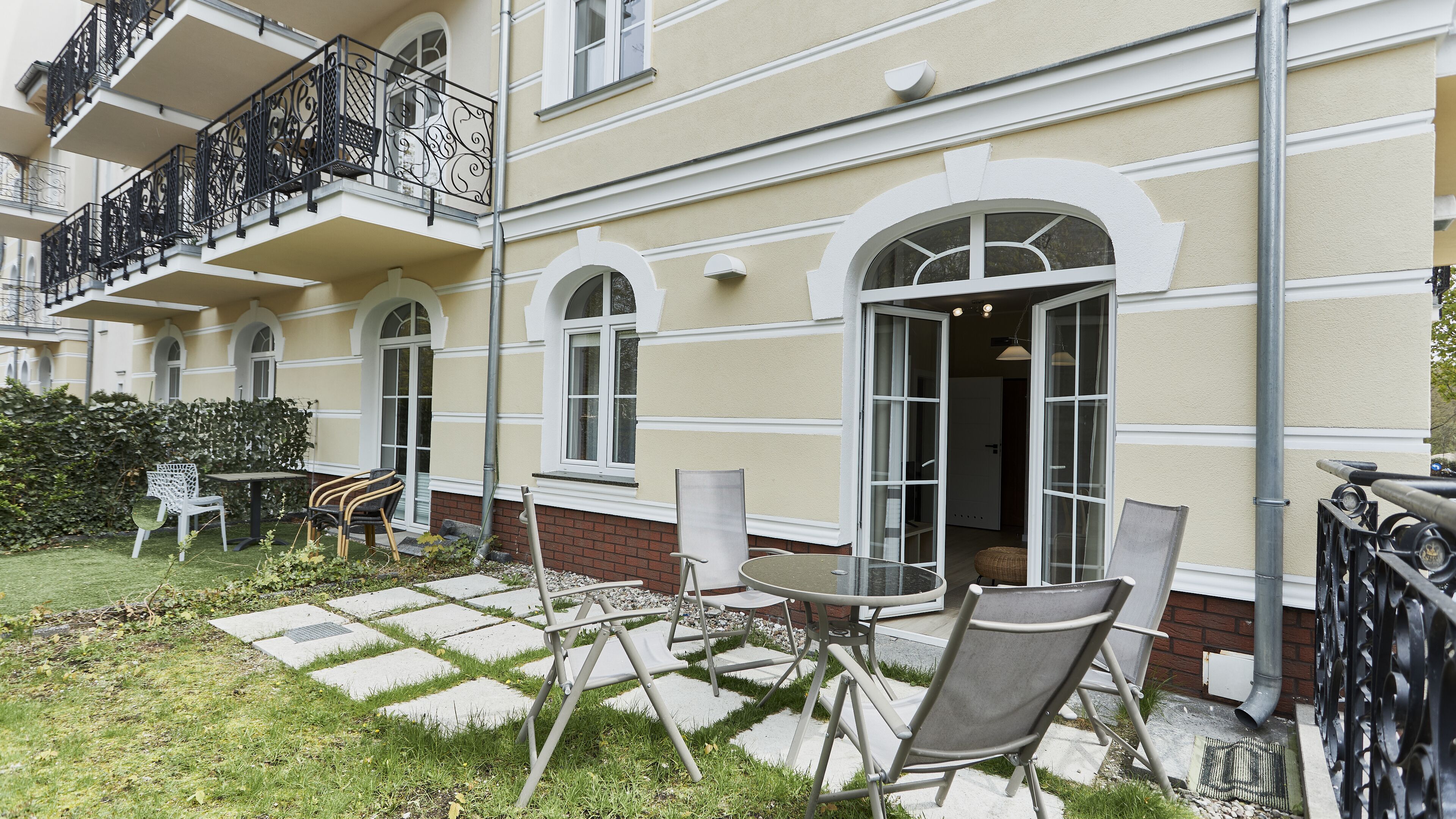 A courtyard with outdoor seating, a brick wall, and a building with balconies and large windows.