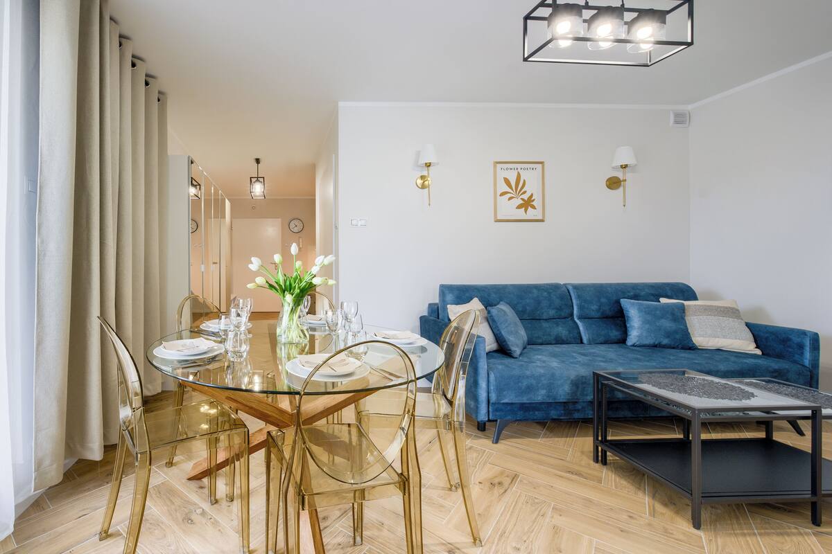 Un salon moderne avec une table à manger en verre, un canapé bleu et une table basse.